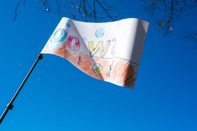「oowa」と書かれた手作りの旗が青空に高くあがっている。